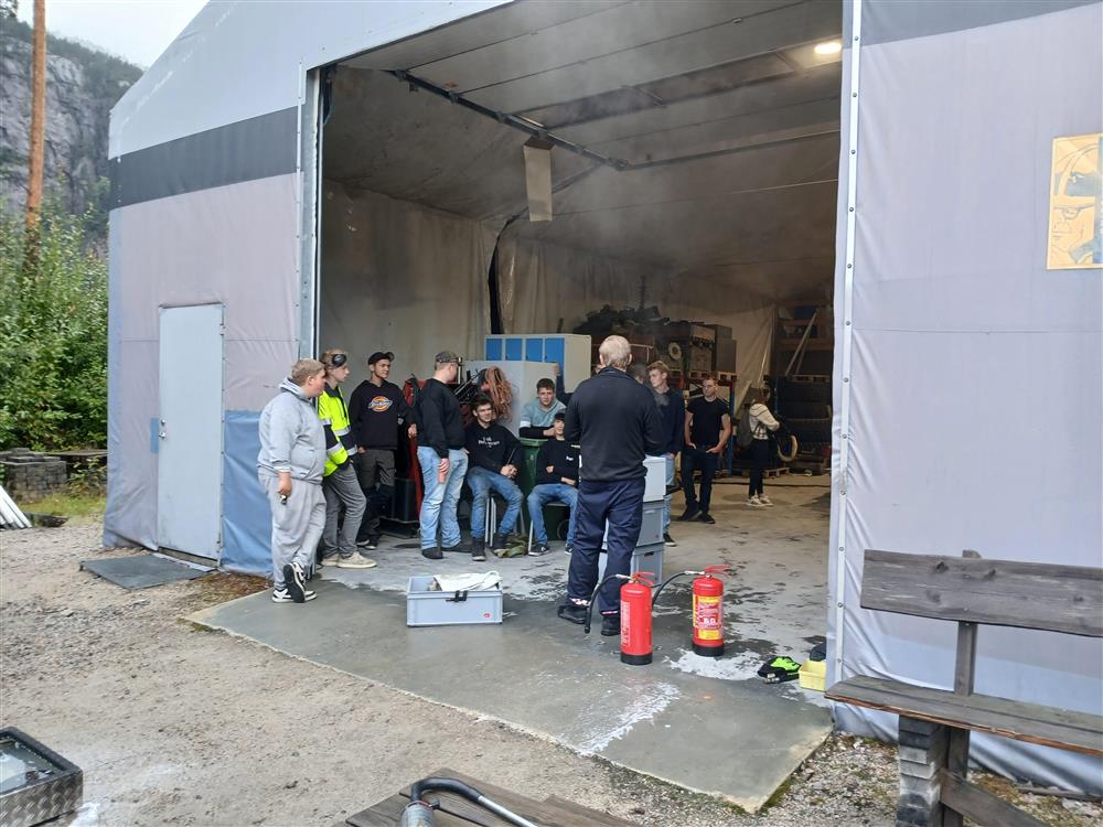 elever står inne i en lagerhall rundt brennbart materiale.foto - Klikk for stort bilde